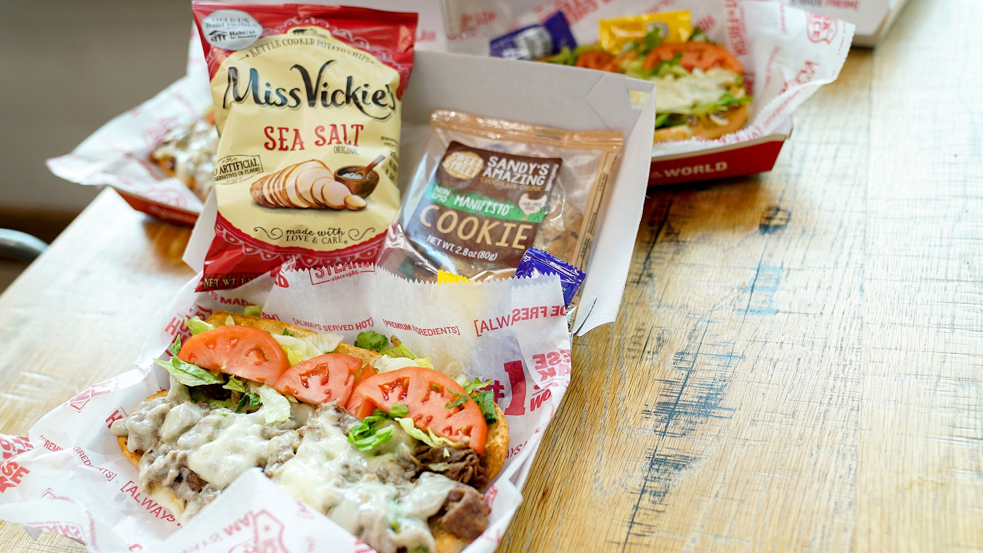Boxed lunches from Charleys catering, including a cheesesteak, chips, and a cookie.